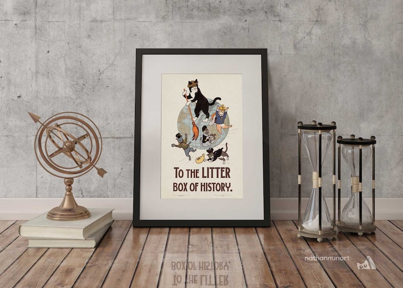 May include: A framed art print with a humorous illustration of cats on a globe, accompanied by the text "TO THE LITTER BOX OF HISTORY." The print is in a black frame, displayed with a brass armillary sphere, books, and hourglasses.