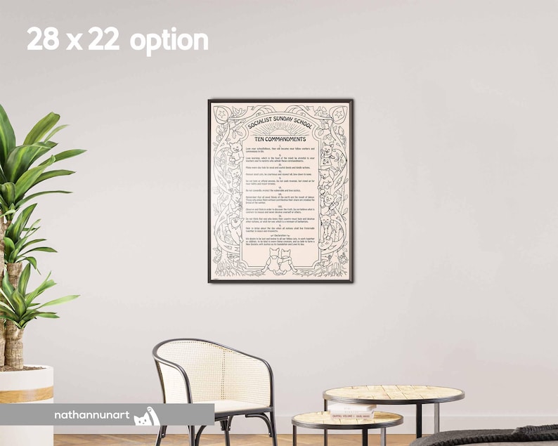 May include: A framed print with the text "Socialist Sunday School Ten Commandments" in black. The print has decorative borders and illustrations. The frame is black, and the print is displayed on a white wall.