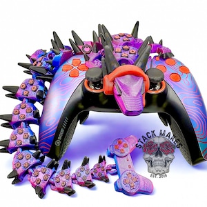 May include: Custom gaming controller with a dragon-inspired design. The controller features a black base with purple and blue accents, orange buttons, and a dragon head. Additional dragon-scale attachments are included. The logo "STACK MAKES" is visible.