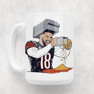 May include: White ceramic mug featuring a cartoon illustration of a football player wearing a grater on his head and grating cheese. The player is wearing a black and orange jersey with the number 18. The mug has a white handle.