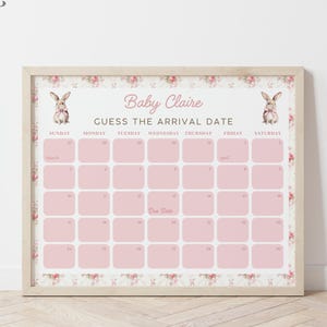 May include: A framed pink and white baby shower game board with the text "Baby Claire Guess the Arrival Date". The board features a calendar grid with bunny illustrations and floral accents.