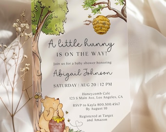 May include: A rectangular baby shower invitation card featuring a watercolor illustration of a bear sitting by a tree with a honey pot and a beehive. The text reads A little hunny IS ON THE WAY! honoring Abigail Johnson on Saturday Aug 20 at 12 PM.