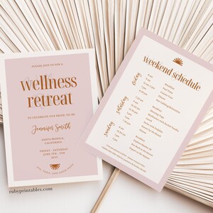 Op de afbeelding: Een roze en witte uitnodiging met een gouden zon-afbeelding en de tekst "wellness retreat" om een aanstaande bruid te vieren. De uitnodiging bevat de naam van de aanstaande bruid, de locatie en de data van de retraite. Een aparte roze kaart geeft een weekendprogramma met activiteiten zoals ontbijt, yoga, zwemmen met dolfijnen en diner.
