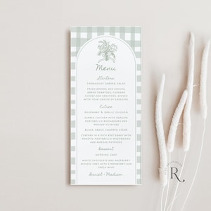 Op de afbeelding: Een verticale menukaart met een lichtgroene gingham patroonrand. Het menu bevat een bloemenillustratie bovenaan en geeft voorgerechten, hoofdgerechten en dessertopties weer. De tekst bevat "Farmhouse Garden Salad" en "Wedding Cake."
