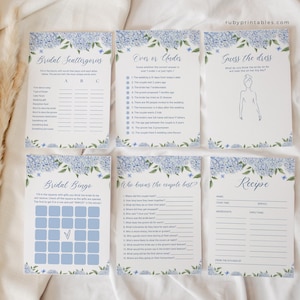 Puede incluir: Seis tarjetas de juegos para una despedida de soltera con un dise&ntilde;o floral azul. Los juegos incluyen "Bridal Scattergories", "Over or Under" y "Guess the Dress". El sitio web "rubyprintables.com" es visible. Para una boda.