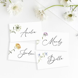 Peut inclure: Quatre cartes de place blanches avec des illustrations florales et des noms &eacute;crits &agrave; la main&nbsp;: Amelia, Jordan, Mandy et Bella.