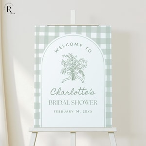 Pode incluir: Uma placa de boas-vindas para um chá de panela, com um fundo de padrão xadrez vichy verde claro. A placa inclui o texto "Welcome to Charlotte's Bridal Shower" com uma ilustração floral e a data 14 de fevereiro de 20xx.