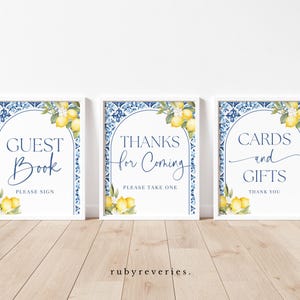 Puede incluir: Tres letreros enmarcados con bordes blancos. Cada letrero tiene un diseño de azulejos azules y blancos, acentos de limón y flores, y el texto "Guest Book", "Thanks for Coming" y "Cards and Gifts".