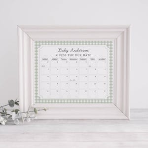 May include: A white framed calendar with a green and white gingham pattern. The calendar is titled "Baby Anderson Guess the Due Date" and has the months of March and April displayed.