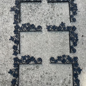 Puede incluir: Seis escuadras de esquina de metal negro con un diseño decorativo de vid. Cada escuadra tiene forma de L y presenta hojas y racimos de uvas detallados. Las escuadras están diseñadas para el montaje.