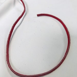 May include: A red leather cord with a white edge.