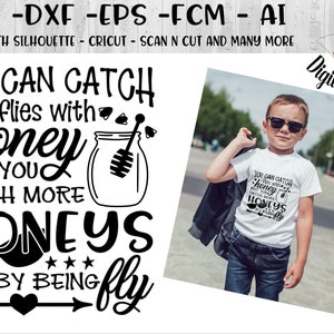 May include: Black and white graphic design with the text "You can catch flies with honey but you catch more honeys by being fly". The graphic also includes a jar of honey and a bee. The graphic is on a white t-shirt being worn by a young boy.