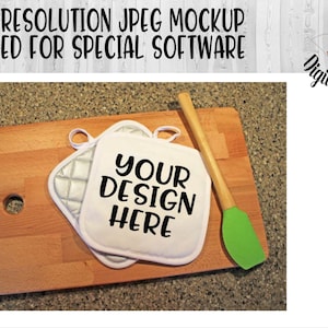 May include: Two white oven mitts with a silver quilted design on a wooden chopping board. The mitts have black text that says "YOUR DESIGN HERE". A green silicone spatula is also on the board.