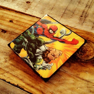 May include: A comic book cover featuring a green and black superhero fighting a red and blue superhero with tentacles. The background is yellow with a radial pattern.