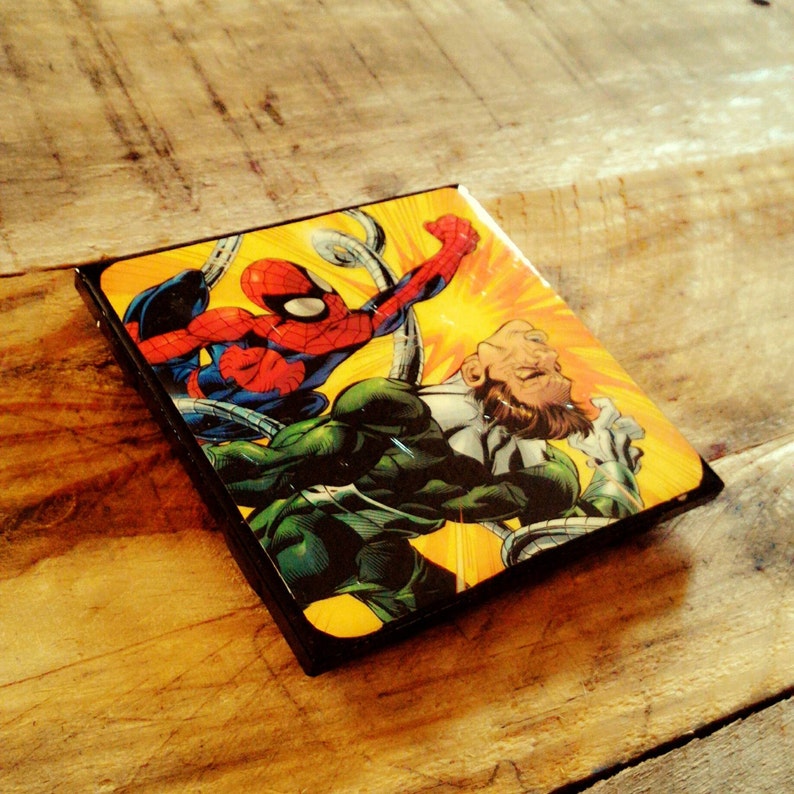May include: A comic book cover featuring a green and black villain with a red and blue superhero on top of him. The villain has six arms and is holding a weapon. The superhero is wearing a mask and has a red spider symbol on his chest.