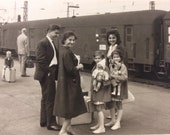 Old photo two little twin girls going on a train ride with suitcases and dollies, parents, cute antique candid family black white photograph