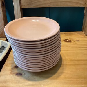 K&ouml;nnte beinhalten: Ein Stapel hellrosa Keramik-Dinnerteller.