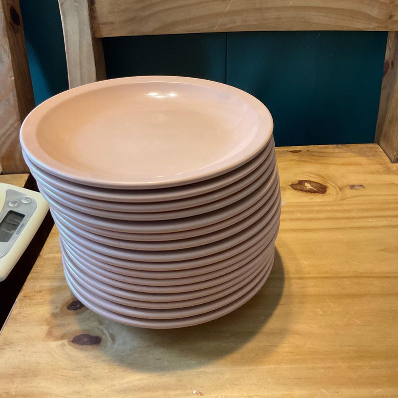 K&ouml;nnte beinhalten: Ein Stapel hellrosa Keramik-Dinnerteller.