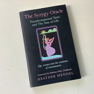 May include: The Syzygy Oracle: Transformational Tarot and The Tree of Life book cover features a black background with a colorful illustration of a fairy-like figure with wings and a purple dress. The text on the cover reads "The Syzygy Oracle: Transformational Tarot and The Tree of Life".