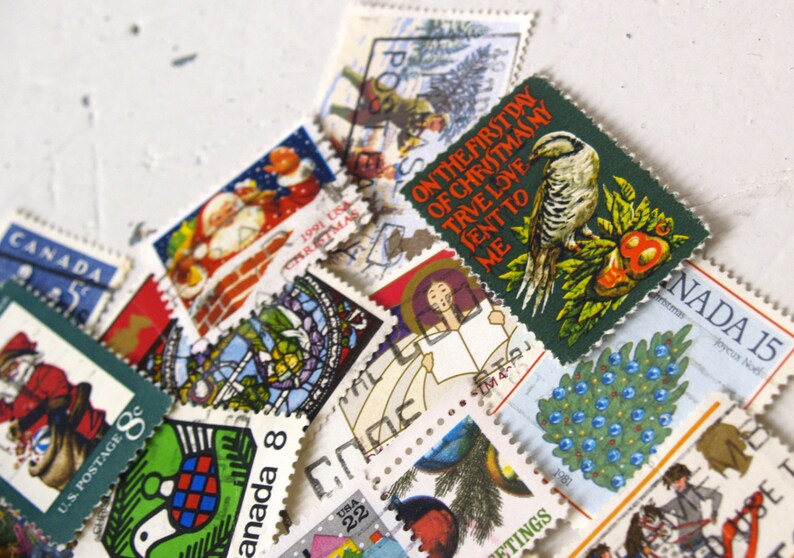 May include: A collection of vintage Christmas stamps featuring a variety of designs, including a bird on a branch, a Christmas tree, and a Santa Claus. The stamps are in various colors, including red, green, blue, and white. The text on the stamps reads "On the first day of Christmas my true love sent to me..." and "Canada 15".