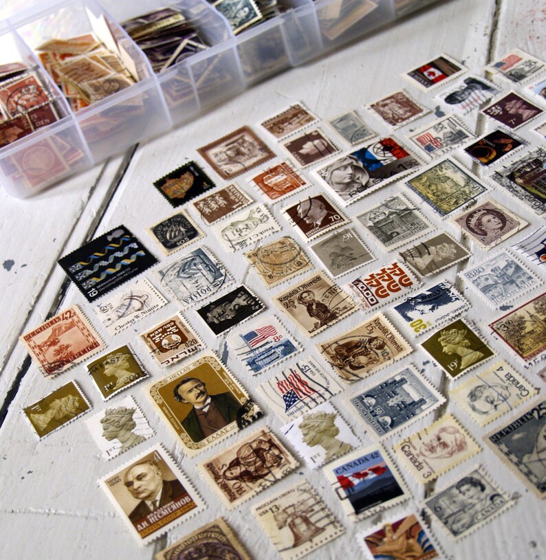 May include: A collection of vintage postage stamps from around the world, featuring a variety of designs and colours. The stamps are arranged in a grid pattern on a white surface. Some of the stamps feature images of people, animals, and landmarks.