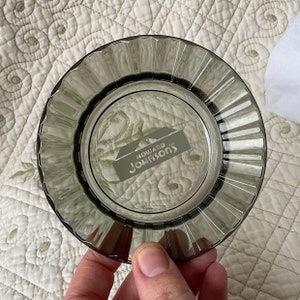 May include: A clear glass ashtray with a fluted edge. The ashtray has a white logo that reads "Howard Johnson's" with a house icon.