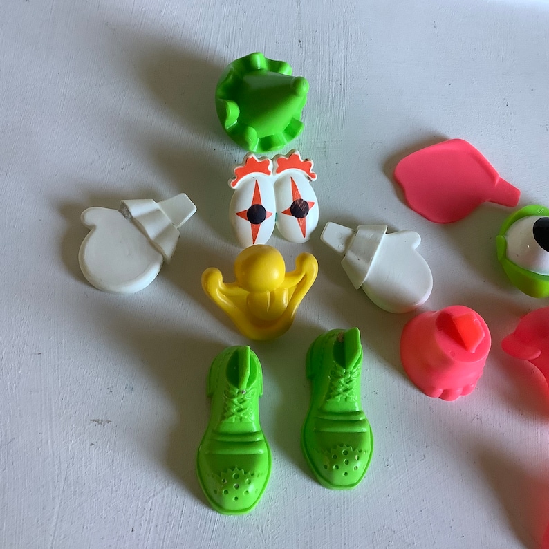Może przedstawiać: Zestaw kolorowych plastikowych zabawek do zabawki z głową ziemniaka. Zestaw zawiera zielony kapelusz, dwa zielone buty, dwie białe rękawiczki, ż&oacute;łty nos, dwa czerwone oczy z czarnymi źrenicami, r&oacute;żowe usta i r&oacute;żowe ucho.