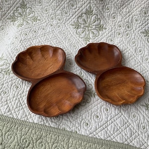 Peut inclure: Deux plats de service en bois en forme de coquillages. Les plats sont de couleur marron et ont une finition en bois naturel. Ils sont assemblés pour créer un plat de service divisé.