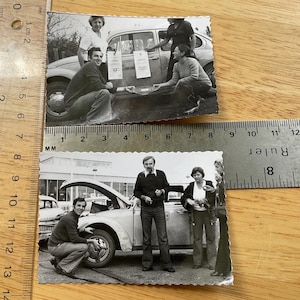 May include: Two black and white photographs depicting people with vintage cars. One shows people inspecting a car with awards attached. The other shows people standing near a car with the bonnet open.