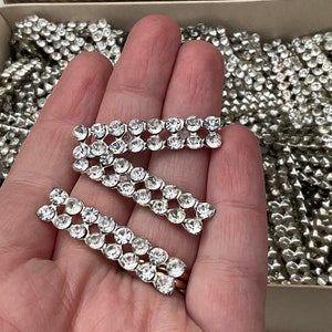 Può includere: Tre pezzi di bordura in strass argentati con strass trasparenti. I pezzi di bordura sono disposti a scalare su una mano.