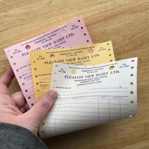 May include: A hand holds three vintage Pleasant View Dairy Ltd. receipts in pink, yellow, and cream colors. The receipts have perforated edges and include text such as "Pasteurized Milk and Cream" and "Creamery Butter."