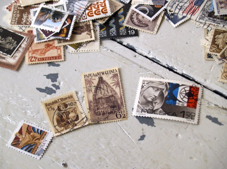 May include: A collection of vintage postage stamps from various countries, including Canada, Denmark, Papua New Guinea, Poland, and the Philippines. The stamps feature a variety of designs, including a hut, a woman's face, and a ship.