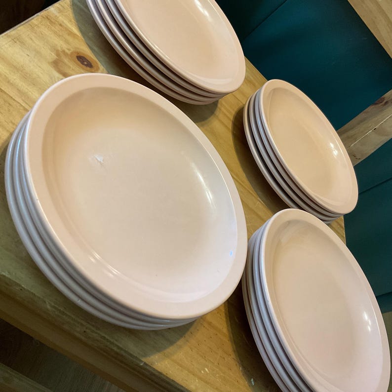 K&ouml;nnte beinhalten: Ein Satz mit vier Stapeln rosafarbener Keramik-Dinnerteller. Jeder Stapel hat sechs Teller.
