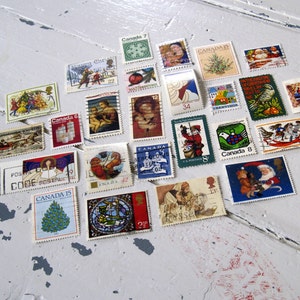 May include: A collection of vintage Canadian Christmas stamps featuring various holiday themes, including Santa Claus, winter scenes, and festive greetings. The stamps are arranged in a heart shape on a white surface.