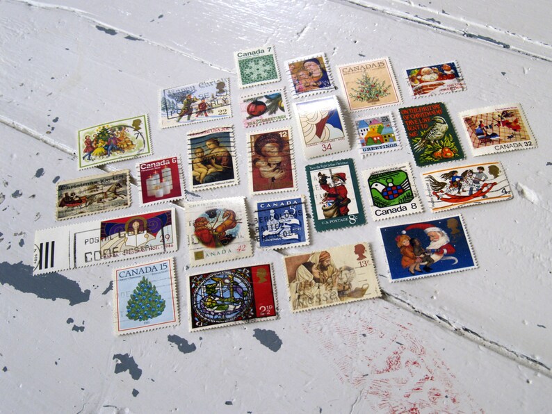 May include: A collection of vintage Canadian Christmas stamps featuring various holiday themes, including Santa Claus, winter scenes, and festive greetings. The stamps are arranged in a heart shape on a white surface.