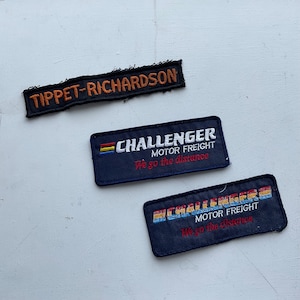 May include: Three embroidered patches with blue fabric and white text. The top patch is orange and black with the text "TIPPET-RICHARDSON". The middle patch has red, yellow, and blue stripes and the text "CHALLENGER MOTOR FREIGHT We go the distance". The bottom patch has red, yellow, and blue stripes and the text "CHALLENGER MOTOR FREIGHT We go the distance".