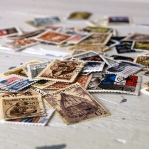 May include: A collection of vintage postage stamps from around the world, featuring various designs and colours. Some stamps include text such as "Republik Osterreich" and "Papua New Guinea".