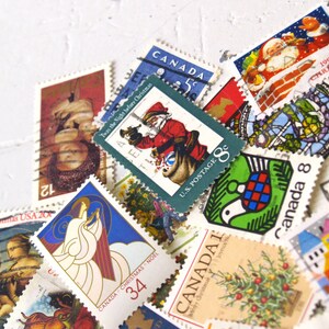 May include: A collection of vintage Christmas stamps featuring various designs, including a Santa Claus, a dove, a Christmas tree, and a stained glass window. The stamps are from Canada and the United States, and some feature the text "Twas the Night Before Christmas" and "Canada Christmas Noel".