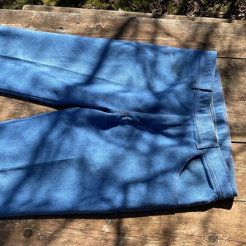 Op de afbeelding: Een paar blauwe denim jeans gevouwen in de helft, met de voor- en achterzakken zichtbaar. De jeans is lichtblauw gewassen en heeft een klassieke rechte pijp.