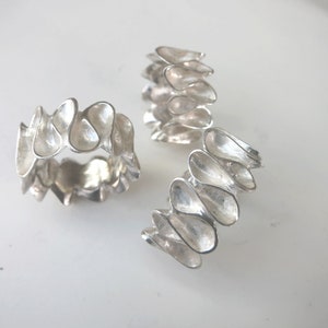 K&ouml;nnte beinhalten: Drei silberne Ringe mit einem einzigartigen, organischen Design. Jeder Ring besteht aus einer Reihe von miteinander verbundenen, tropfenf&ouml;rmigen Teilen.