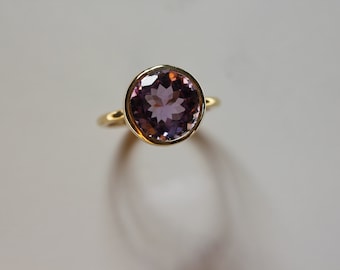 May include: A gold ring with a large, round, purple amethyst gemstone.