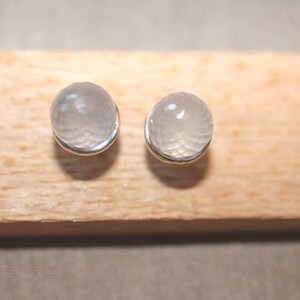 May include: A pair of silver stud earrings with clear, faceted, round gemstones.