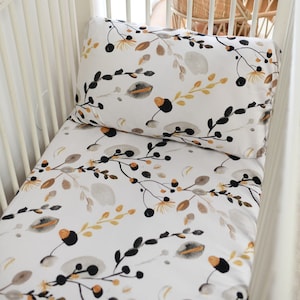 May include: A white cot sheet with a floral pattern featuring black branches, grey leaves, and yellow flowers.