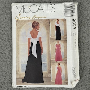 May include: McCall's Evening Elegance sewing pattern. The pattern includes designs for formal gowns. The main image shows a black and white gown with a bow detail. The pattern size is FW (18, 20, 22).