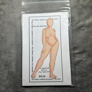 May include: A sewing pattern for a plus size cloth doll body in a clear plastic bag. The paper insert features a drawing of a human figure with text stating: This Pattern Contains No Costume, Plus Size Body Basic, Mary Tressler 2007, $15.00.