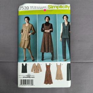 May include: A Simplicity sewing pattern envelope 2539, size AA 10-18, featuring illustrations of three outfits: a tan jacket and skirt set, a floral print sleeveless dress over a black turtleneck, and a dark vest with matching trousers.
