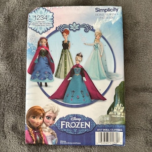 May include: A Simplicity home sewing pattern for 11.5-inch doll clothes featuring Disney's Frozen characters. The pattern includes illustrations of doll dresses and capes. The package has the text "1234" and "Disney Frozen".