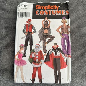 Könnte beinhalten: Simplicity Costumes Nähmuster Nummer 9802 für die Größen A, S, M und L. Das Muster enthält Anleitungen und Vorlagen für die Herstellung von sechs Kostümen: ein Pirat, eine Bauchtänzerin, ein Dschinn, ein Vampir, eine Ballerina und der Weihnachtsmann.