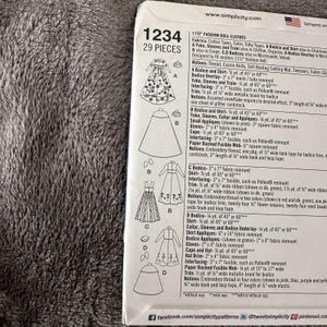 May include: A Simplicity pattern sheet for 11.5" fashion doll clothes, featuring illustrations of various doll dresses and accessories. The pattern includes instructions and fabric requirements for creating multiple doll outfits. The sheet is white with black text.