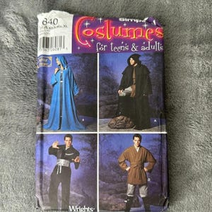 May include: A Simplicity sewing pattern envelope labelled 840 for Costumes for teens & adults. The package displays four costume variations: a blue hooded robe, a black hooded cloak, a black martial arts style outfit, and a brown belted tunic.